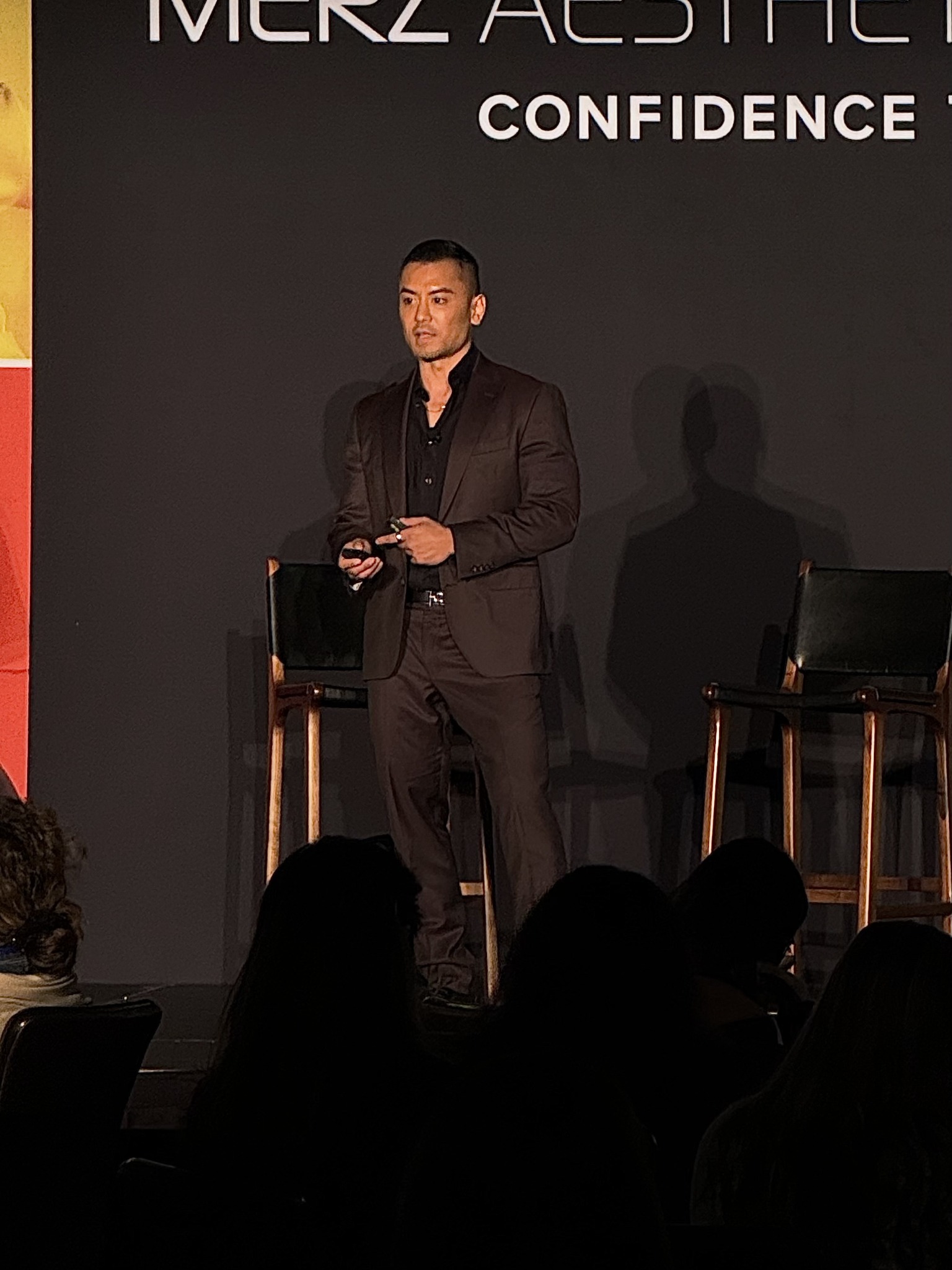 Dr. McKee speaking on stage at an aesthetics event